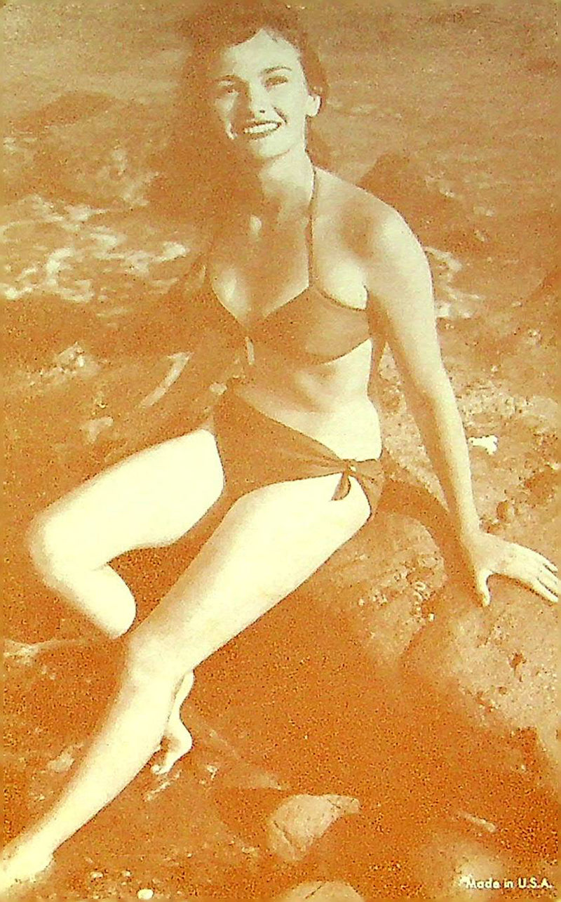 US 50s Pin Up Promo Photo Card Woman Bikini Swimsuit Sitting Rocks Beach Shore